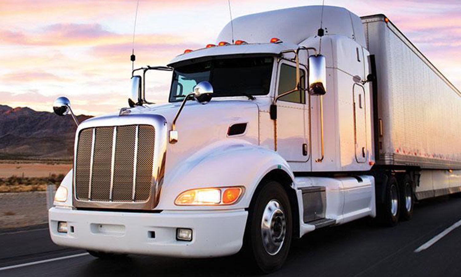 White semi truck on highway with sunrise