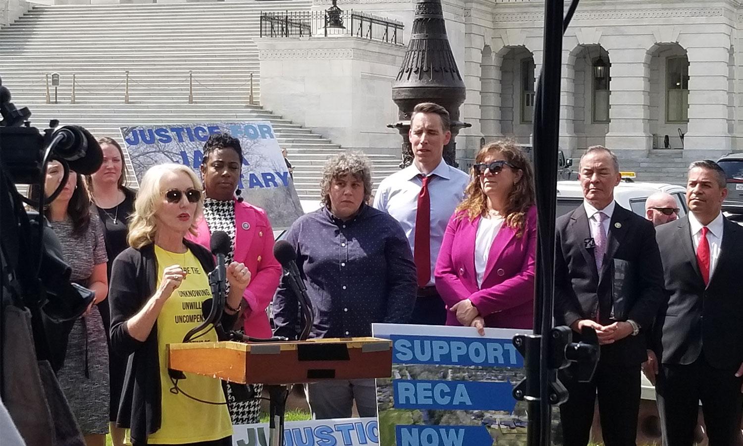 People gathered around a podium outdoors during a press conference.