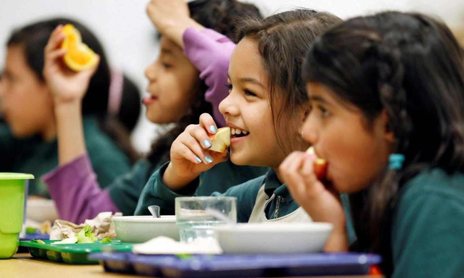 Girls eating fruit in a school cafeteria