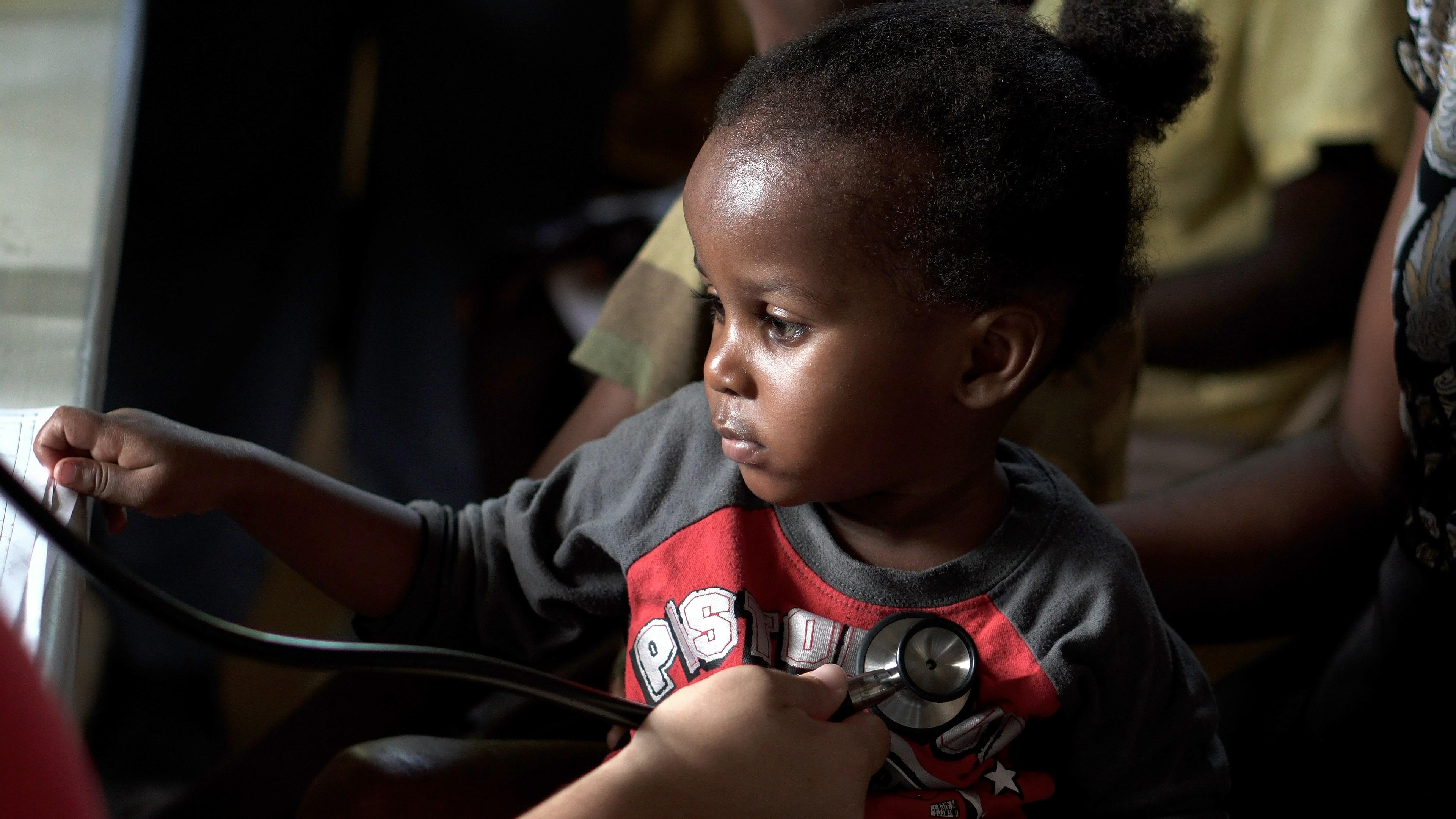 a child with grey and red sweatshirt and stethoscope