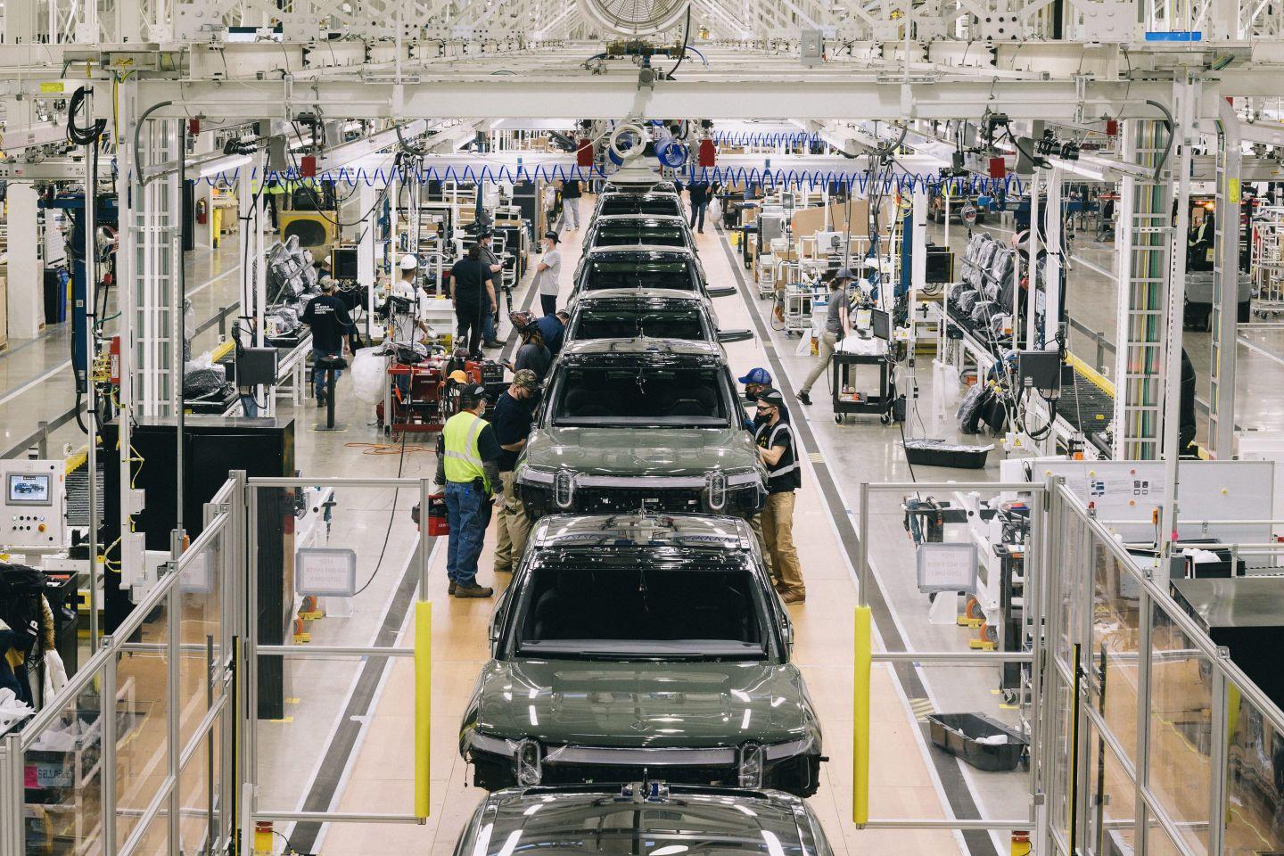 An assembly line of green rivian electric pick up trucks