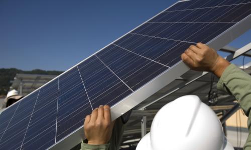 A person installs a solar panel.
