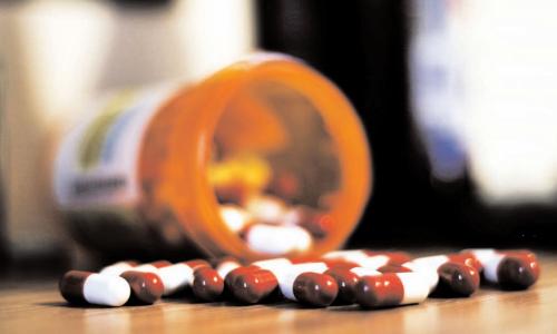 Pill bottle with pills spilled on table