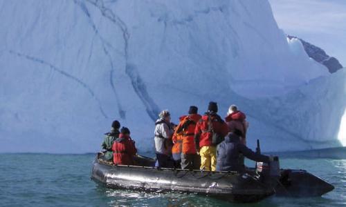 A research team in a raft examines a glacier