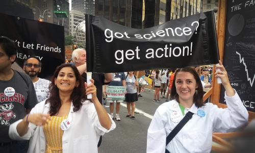 Two scientists holding a sign that says "Got Science? Get Action!"