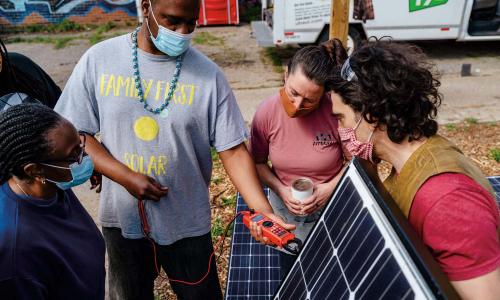 Highland Park community residents inspect a solar panel.