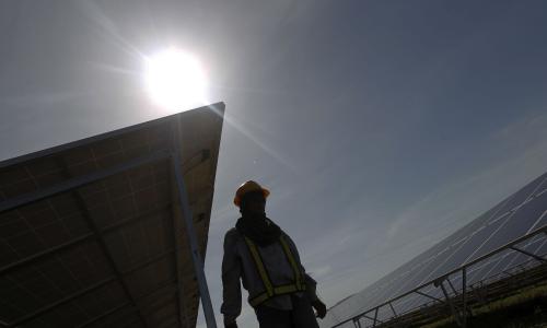 A person walking past solar panels in the heat