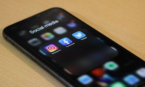A smart phone on a table with the Instagram, Facebook, and Twitter apps visible.