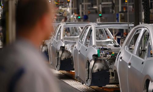 A person looks at cars inside of a factory.