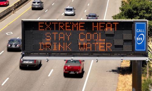 A road sign that reads "Extreme heat. Stay cool. Drink water."