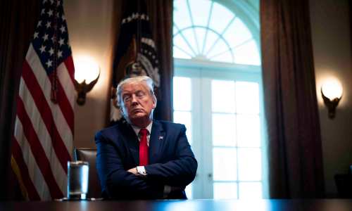 President Trump sitting at a table with his eyes closed and arms crossed.