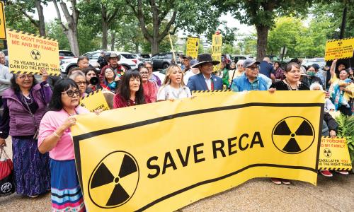 People standing behind a sign that reads "SAVE RECA"
