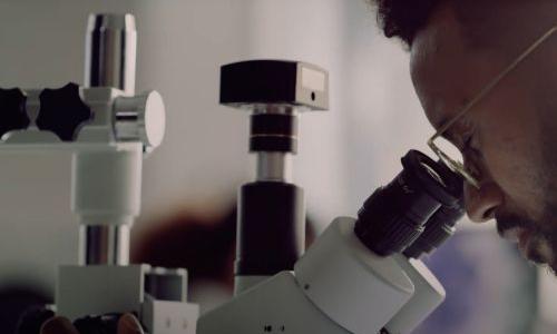 thumbnail of scientist peering into microscope