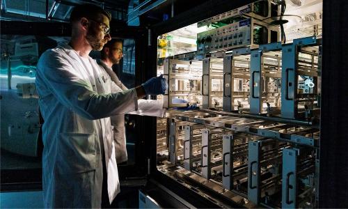 A Volkswagen employee demonstrates how to insert a multi layer cell test pouch in a battery cell test chamber for electric car battery at the pilot project for Volkswagen's own electric car battery production facility