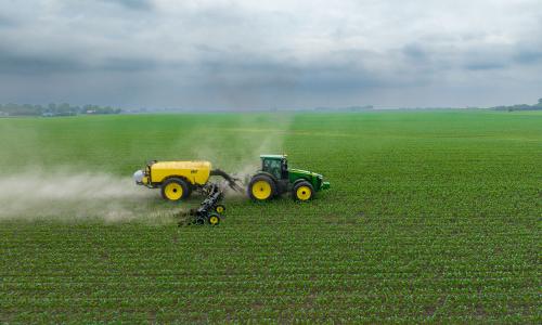 A tractor spraying fertilizer on a field.