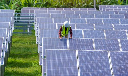A worker installing solar panels at a solar power station.