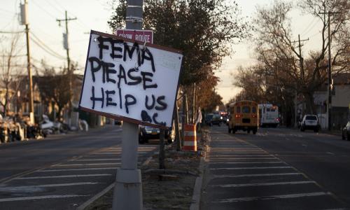 A sign on the street that reads "FEMA PLEASE HELP US"
