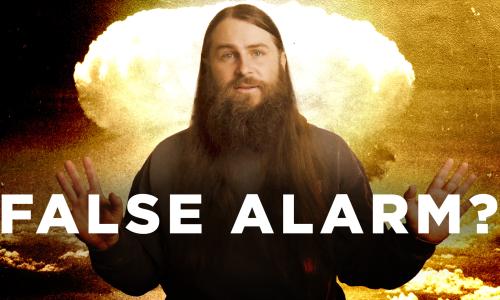 A person standing in front of an image of a mushroom cloud behind text that reads "False alarm?"