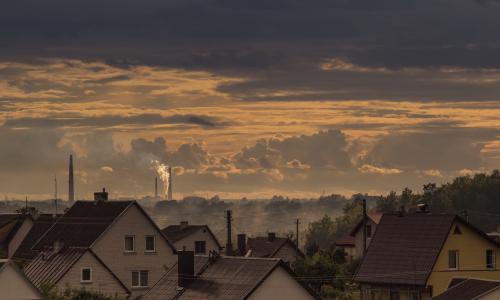 A view of homes with smokestacks in the background