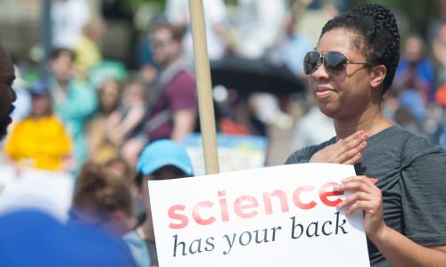 Person holding a sign that says "Science has your back"