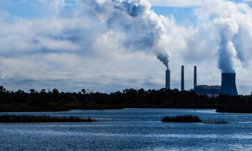 A skyline with power plants emitting smoke.